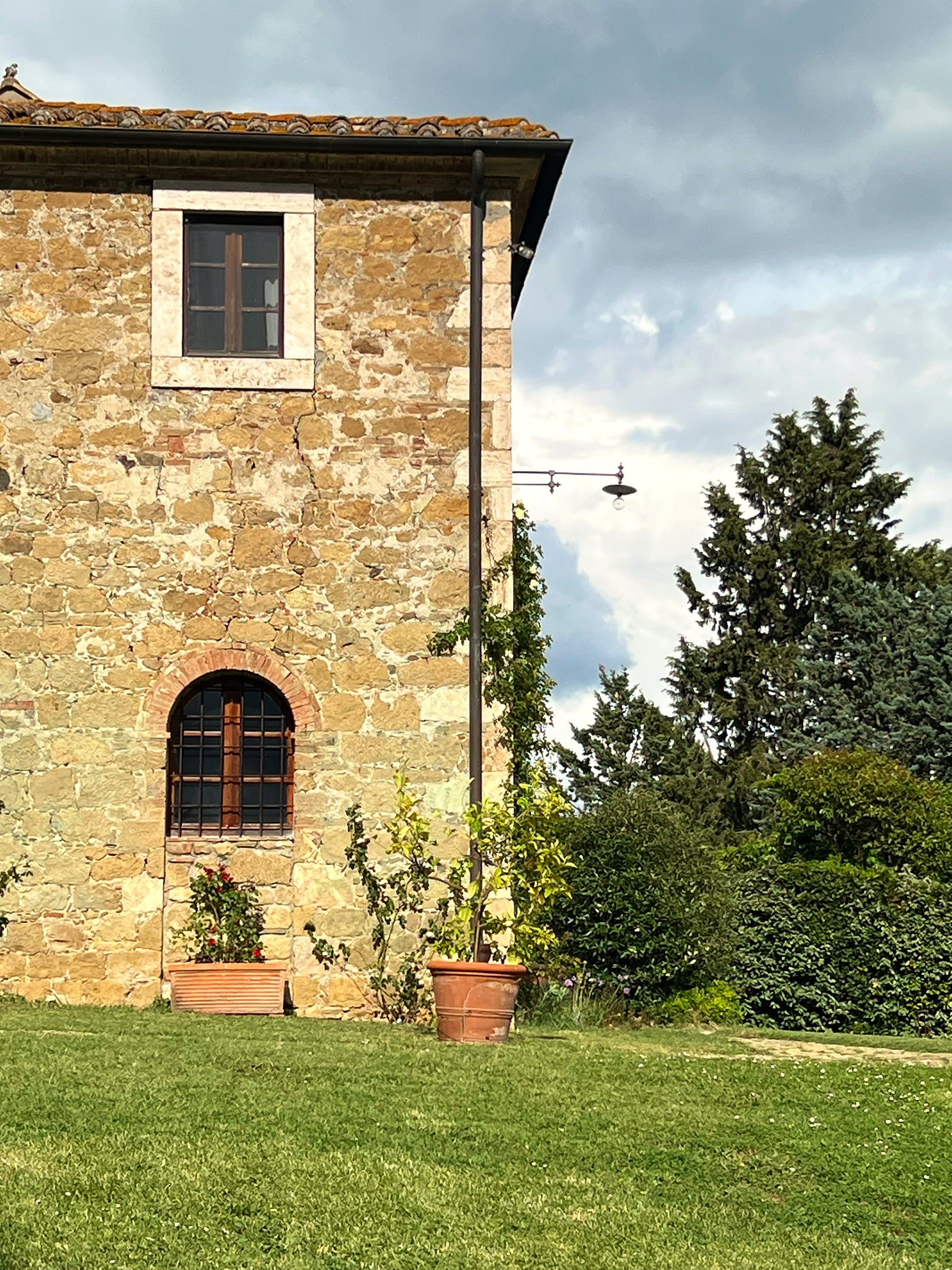 Stone facade of the villa with arched window and potted flowers