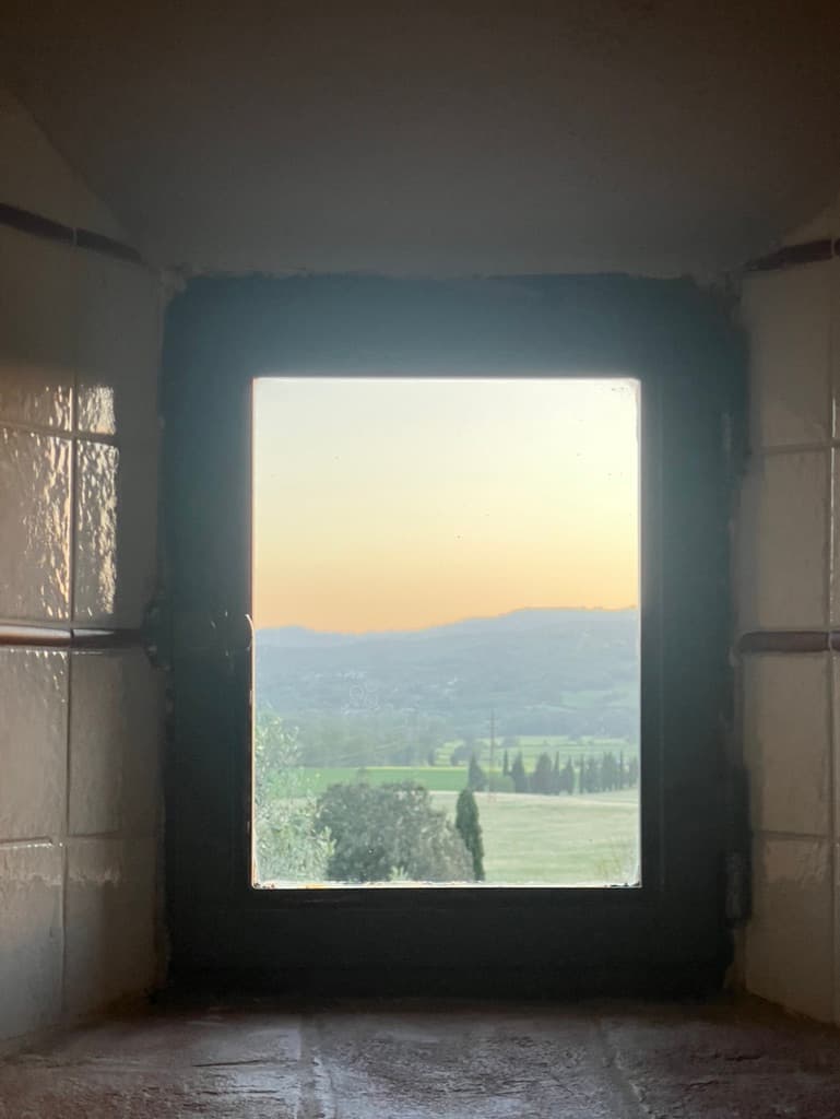 Stone window with golden hour view of Val d'Orcia