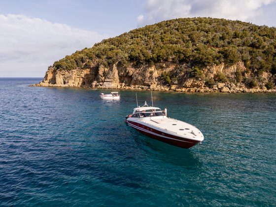 The boat anchored below green cliffs